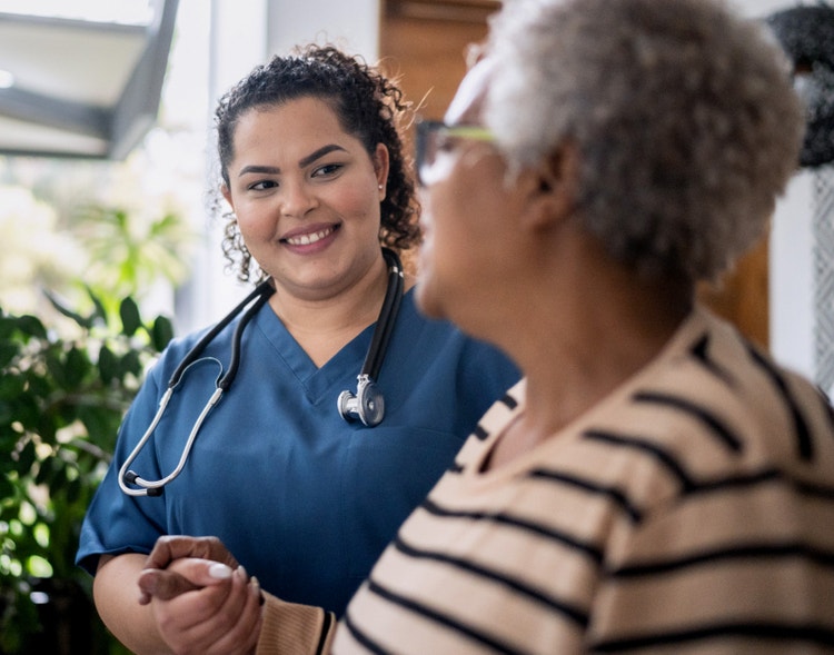 A healthcare worker holding the hand of an elderly patient