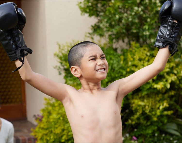 A young, gloved boxer with raised arms