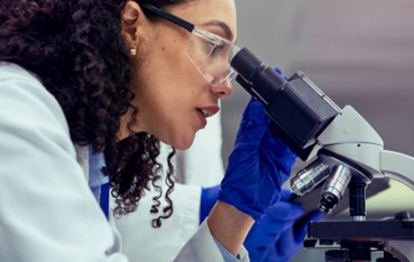 A woman in a lab coat looking into a microscope