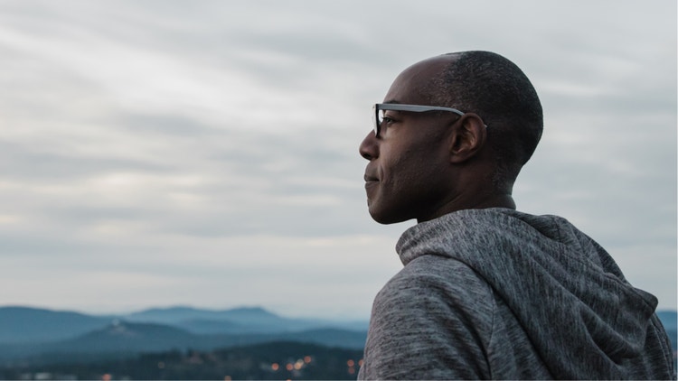 A black man looking forward toward mountains