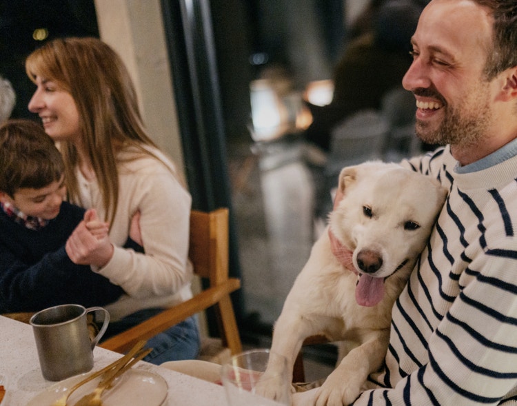 A family of three and their dog smiling at a dinner table
