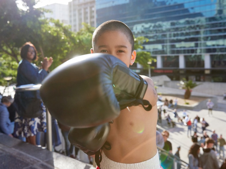 A young, gloved boxer punching forward