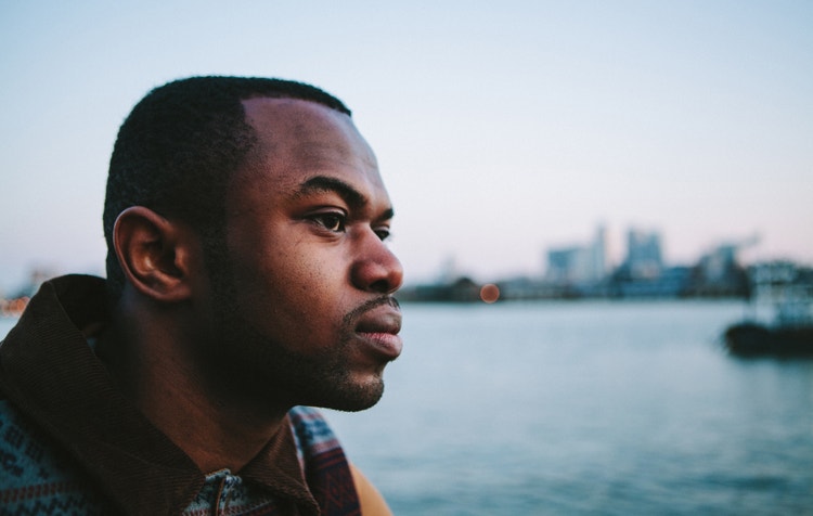 A black man looking out near a marina